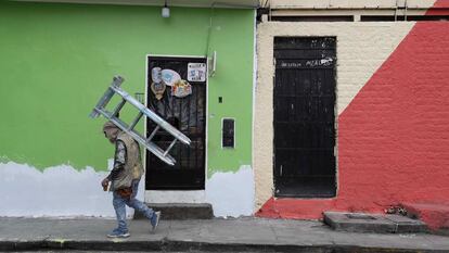 Um pintor de paredes caminha com uma escada nas costas enquanto trabalha nas fachadas das casas de San Cristóbal, em 18 de agosto passado, em Lima.