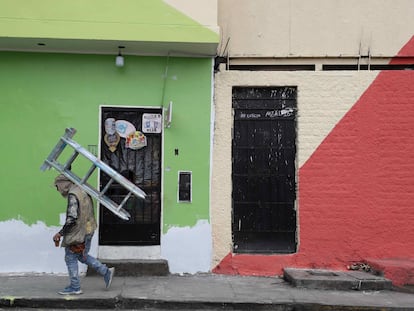 Un pintor de casas camina con una escalera mientras trabaja en las fachadas de la viviendas del cerro San Cristóbal, el 18 de Agosto de 2021, en Lima.