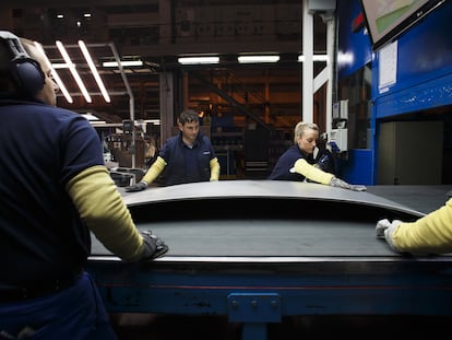 Varios trabajadores pulen manualmente el capó de un coche en la fábrica de Gestamp en Dueñas (Palencia).