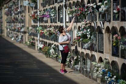 Una mujer deposita flores en el cementerio del Poblenou, en Barcelona.