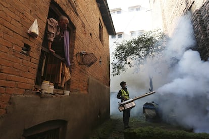 Un hombre nepalés observa a un trabajador fumigar en un intento de controlar la propagación de enfermedades transmitidas por mosquitos en Katmandú (Nepal). Según la División de Epidemiología y Control de Enfermedades del Departamento de Salud, el número de los casos de dengue se ha disparado más del 65% en todo el país en la última semana.