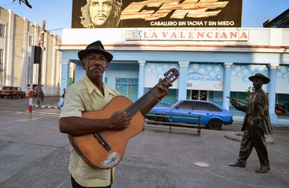 El músico callejor cubano Lázaro Miguel Bernal toca la guitarra junto a la estatua dedicada a Benny Moré.