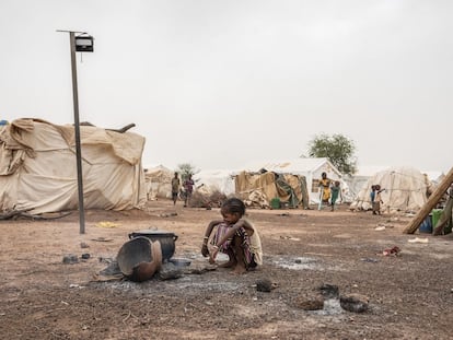 Una niña, frente a una cacerola puesta sobre el fuego en un campo de desplazados por la violencia en Barsalogho, Burkina Faso.