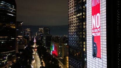 Un integrante del colectivo Hasta encontrarte despliega una manta durante una protesta en contra de la militarización y la desaparición forzada en la cima del monumento Estela de Luz, en Ciudad de México, el 15 de septiembre.