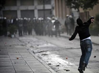 Un joven lanza una piedra a la policía esta mañana en Atenas