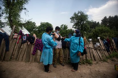 Dos sanitarios administran vacunas de AstraZeneca en Minnar, localidad la norte de Srinagar, India, este jueves.