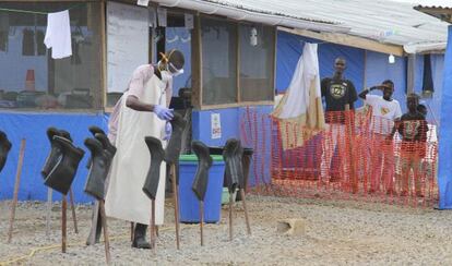 Unos ni&ntilde;os esperan a que se prepara el sanitario encargado de tratarles el &eacute;bola en el condado de Bong (Liberia). 