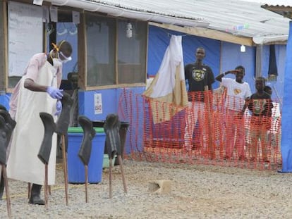 Meninos com ebola observam preparativos do funcionário encarregado de tratá-los, no condado de Bong (Libéria).