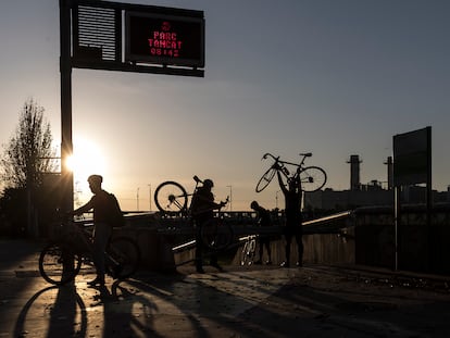 Un grupo de ciclistas saltan la valla de acceso al parque fluvial del Besòs para entrar a pedalear antes de su apertura