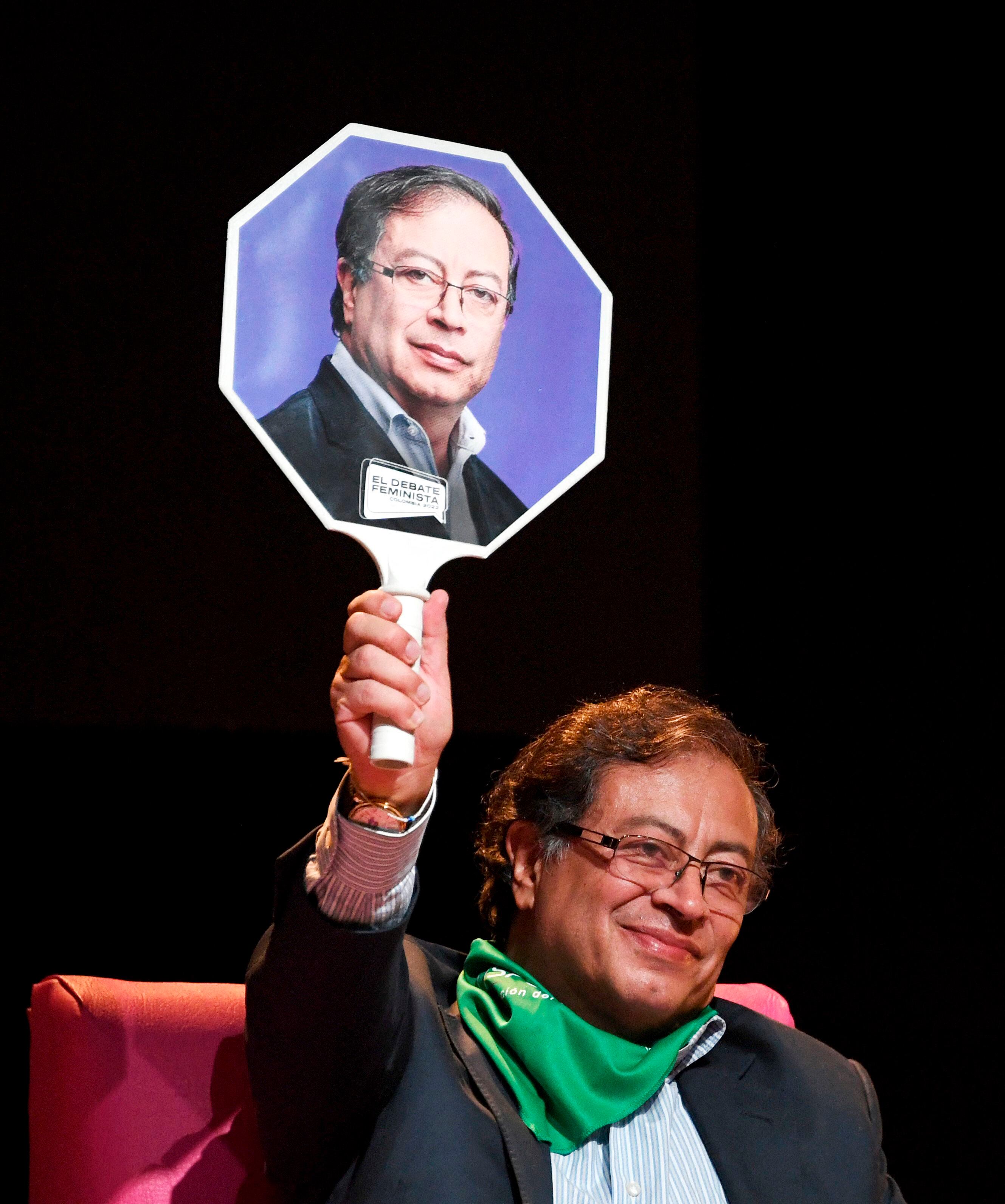 Petro, entonces candidato presidencial, sostiene un cartel con su retrato durante un debate feminista en Bogotá, el 2 de junio de 2022. 