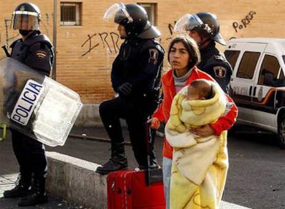 Una mujer sale de su casa con su hijo y una maleta tras el desalojo de un bloque de viviendas del barrio de Virgen del Carmen de Alicante.