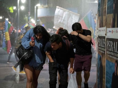 Un grupo de personas huye del cañón de agua utilizado por la policía antidisturbios de Chile, el pasado 17 de diciembre durante una protesta en Santiago.