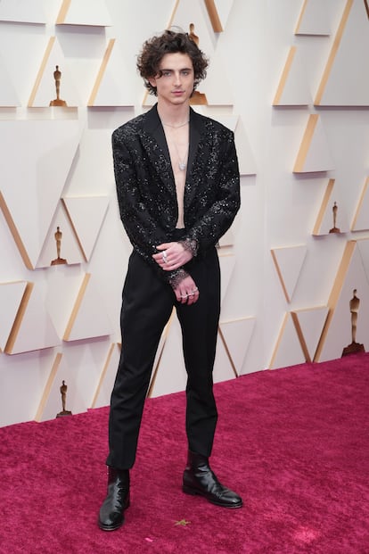 El día que fue a los Oscar con un traje de mujer. En el año 2022 Timothée Chalamet siguió escalando posiciones como uno de los actores más irreverentes en lo que a estilo se refiere. En la alfombra roja de los Oscar decidió llevar un traje de chaqueta de lentejuelas y encaje de la colección femenina de Saint Laurent que Nicolas Ghesquière había presentado en el desfile de primavera-verano 2022. Y no solo eso, sino que posó a pecho descubierto, sin camisa de ningún tipo, adornado únicamente por un colgante y varios anillos de diamantes de Cartier, dejando así uno de los 'looks' más comentados de la noche.
