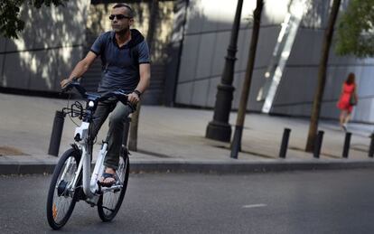 Un usuario de BiciMAD pedalea en su bici por las calles de Madrid.