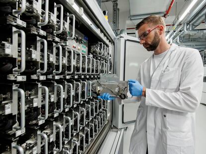 A Volkswagen employee demonstrates how to insert a single cell test pouch in a battery cell test chamber for electric car battery at the pilot project for Volkswagen's own electric car battery production facility on May 18, 2022 in Salzgitter, Germany