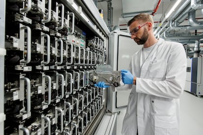 A Volkswagen employee demonstrates how to insert a single cell test pouch in a battery cell test chamber for electric car battery at the pilot project for Volkswagen's own electric car battery production facility on May 18, 2022 in Salzgitter, Germany