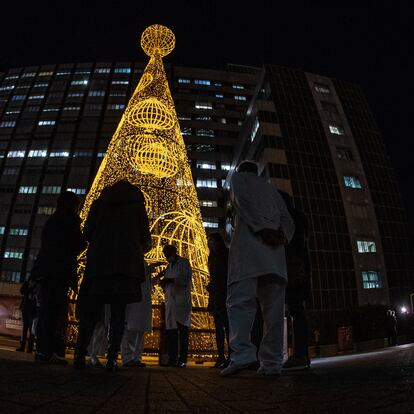 GRAF3035. MADRID, 10/12/2020.- Sanitarios y viandantes observan el árbol de Lotería de Navidad en el hospital de La Paz en Madrid, encendido este jueves como gesto de apoyo y reconocimiento a los profesionales de la sanidad por su encomiable labor ante la pandemia del coronavirus. EFE/Rodrigo Jiménez