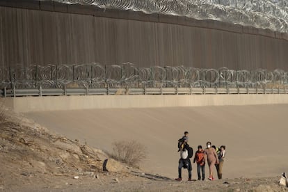 Una familia camina cerca del muro fronterizo buscando una patrulla de inmigración para entregarse.