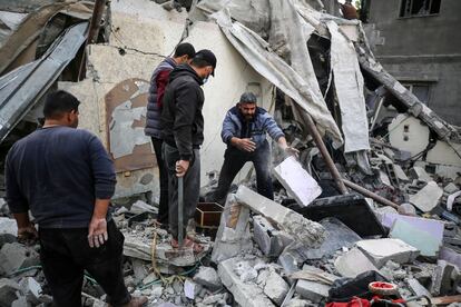 Palestinos buscan entre los escombros de una casa, que estaba siendo utilizada como refugio para una familia desplazada y cuyos miembros murieron durante el ataque, este martes en Deir al Balah. 