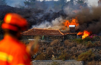 Un miembro de Protección Civil observa cómo se quema una casa debido a la lava en la zona residencial de Los Campitos, en Los Llanos de Aridane.