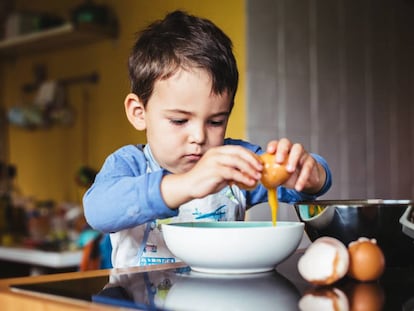 Un niño fríe un huevo. 