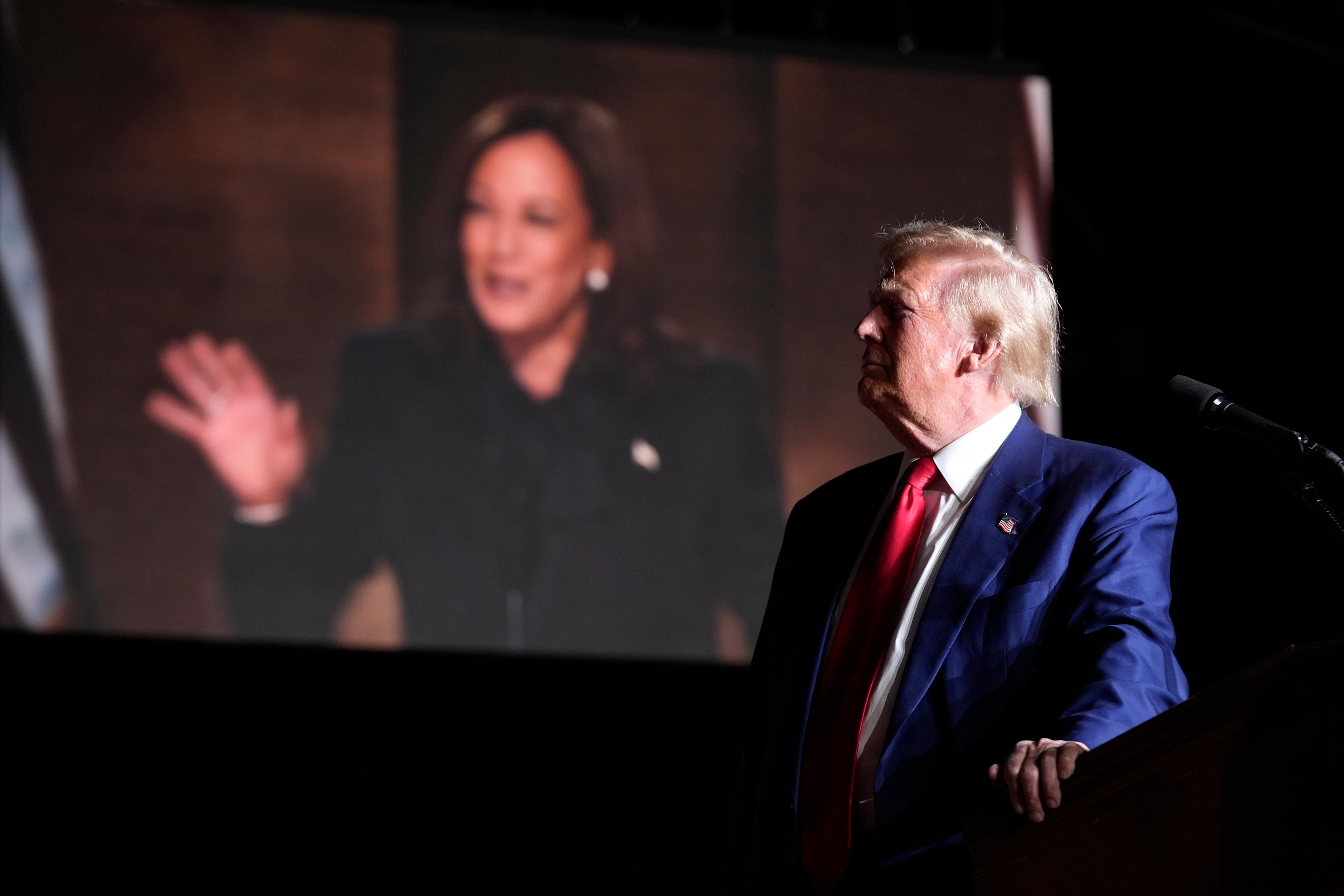 Donald Trump, durante un acto de campaña en Las Vegas, mientras aparece en pantalla Kamala Harris.