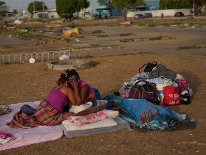 A Venezuelan migrant cries with her daughter after sleeping outdoors in the parking lot of a bus terminal in Boa Vista, Roraima state, Brazil, on April 7, 2023.