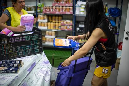 Una joven recoge un paquete de compresas durante el reparto de productos no perecederos en la red solidaria de Latina Carabanchel, este sábado en Madrid.