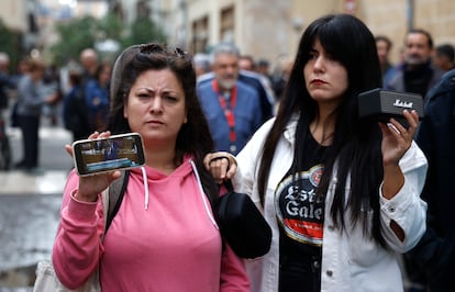 Dos mujeres escuchan la comparecencia de Carlos Mazón, este viernes en el exterior de las Cortes valencianas.