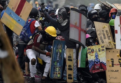 Varios activistas se refugian bajo sus escudos caseros durante los enfrentamientos con la policía en Caracas, el 24 de junio de 2017.