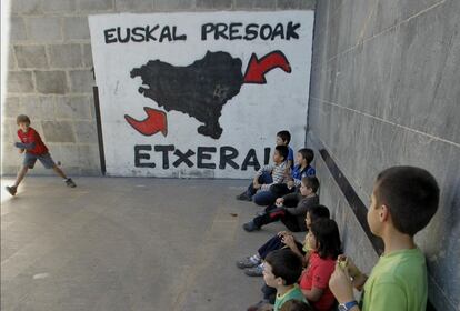 Niños jugando a pelota en el frontón de Elorrio, con una pintada reivindicativa a favor del acercamiento de presos de ETA al País Vasco.