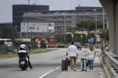 Una pareja de turistas se dirige a pie al aeropuerto de El Prat.