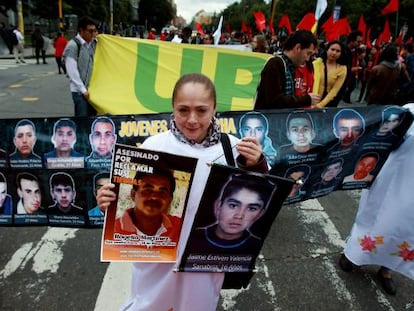 Una mujer sostiene dos fotografías de desaparecidos durante una marcha por las calles del centro de Bogotá (Colombia).