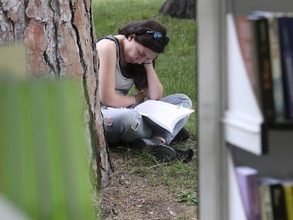 Una mujer lee un libro en un parque.