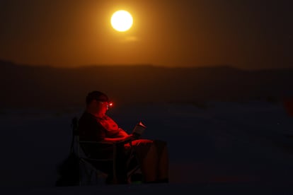 Un hombre lee mientras la superluna aparece este lunes en el Parque Nacional White Sands cerca de la ciudad de Alamogordo, Nuevo México, Estados Unidos.