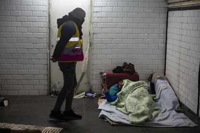 Un voluntario del ayuntamiento se interesa por una persona sin techo en el interior de la Estación del Arte.