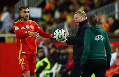 El seleccionador holandés Ronald Koeman entrega un balón al jugador español Óscar Mingueza.