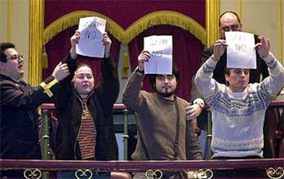 Unos ciudadanos muestran carteles contrarios a la guerra durante el debate en el Congreso.