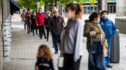 Varias personas esperan para comprar en la plaza de Felipe II de Madrid.