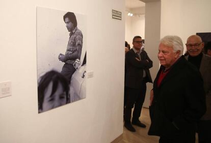 El experesidente Felipe González observa una de sus fotografías de la exposición de Pablo Juliá en Sevilla (detrás).