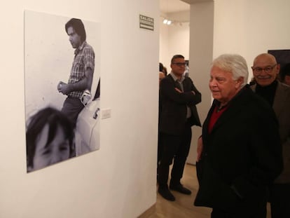 El experesidente Felipe González observa una de sus fotografías de la exposición de Pablo Juliá en Sevilla (detrás).