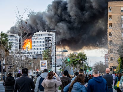 Un grupo de ciudadanos observa el incendio en el edificio del barrio de Campanar, en Valencia, el jueves.