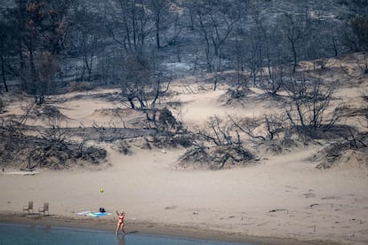 Una mujer juega a la pelota en la orilla de una playa afectada por los incendios forestales en Glystra, en la isla de Rodas, este jueves. 
