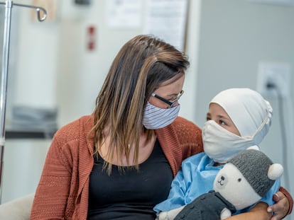 Un niño con cáncer de nueve años sentado junto a su madre en el hospital.