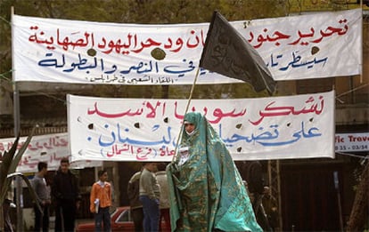 Una mujer libanesa porta una bandera negra frente a carteles a favor de Siria en la ciudad norteña de Trípoli.