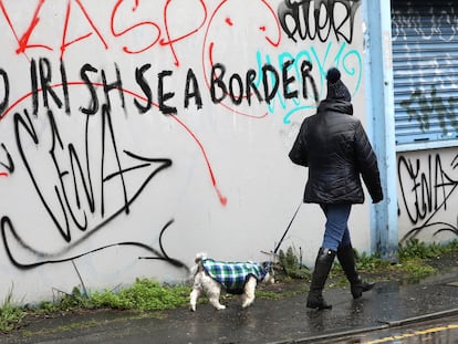 Uma mulher passa diante de um muro de Belfast onde se lê: "Sem fronteiras no mar da Irlanda", nesta quarta-feira.