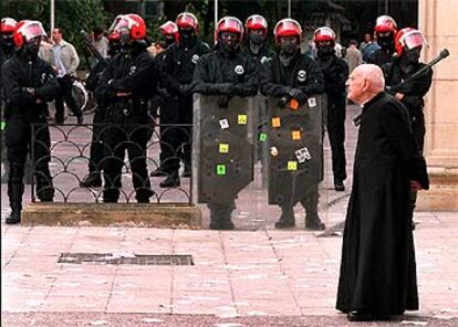 Un sacerdote paseaba ayer frente a una patrulla de agentes de la Ertzaintza desplegados en torno a la sede del Parlamento vasco, en Vitoria.