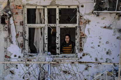 Una mujer mira a través de una ventana de su casa en ruinas, en el distrito de Cizre (Turquía). Los residentes de Cizre empezaron a regresar el miércoles después de que las autoridades levantaran parcialmente el toque de queda vigente desde diciembre por una controvertida operación contra los rebeldes kurdos.