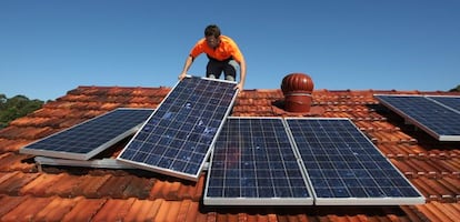 Un técnico instala placas solares en el tejado de una vivienda.