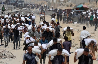 Un grupo de palestinos cargan sacos de comida en Beit Lahia, en el norte de Gaza, este domingo.